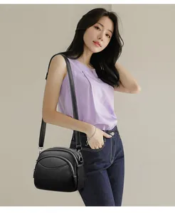 Detail of black pebbled leather crossbody bag with multiple zippers and adjustable strap