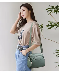Detail of pea green litchi texture PU leather crossbody bag with multi-layer zippers