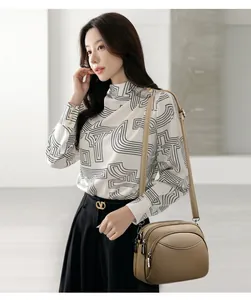 Detail view of khaki PU leather round bag with triple zip layers and adjustable strap