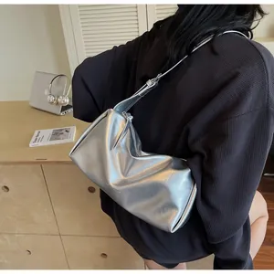 Silberne Falten-Schultertasche mit Metallic-Finish, getragen in einem modernen Büroumfeld