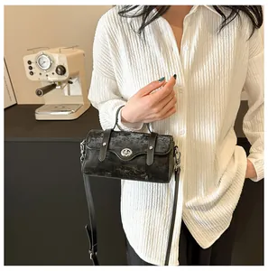 Detail of vintage black cylindrical crossbody bag with silver twist lock and distressed texture
