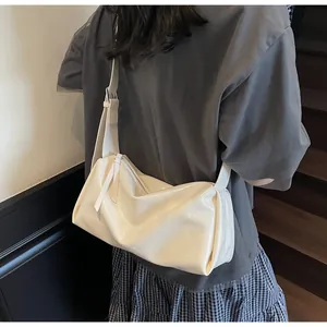 Detailansicht der cremeweißen Schultertasche mit Faltenstruktur an einem Model
