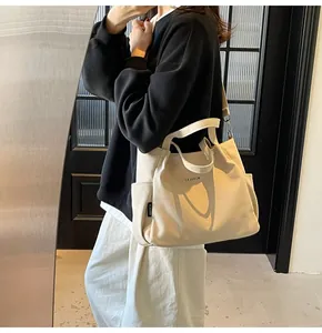 Dettaglio di una grande borsa tote in tela bianco sporco con scritta MIDOLAI e tracolla