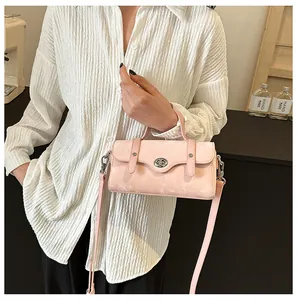 Detail of a light pink crossbody bag with a silver swivel lock and thin leather strap