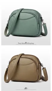 Detail view of tea green and elephant gray textured PU leather crossbody bags with zippers