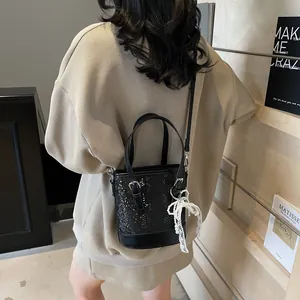 Elegante schwarze Eimer-Tasche aus geprägtem Leder mit Perlen-Schleifen-Anhänger