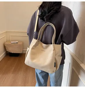 Dettaglio della borsa tote in tela beige con tracolla regolabile e tasca laterale