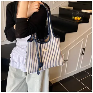 Detail of blue and white striped tote bag with COIN'DDR logo label and long handle