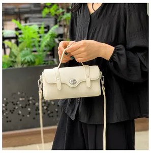 Outdoor look of an ivory leather square bag with a silver swivel lock and shoulder strap