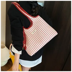 Detailed side view of large red and white striped tote bag with leather tassels and handle
