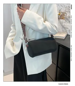 Dettaglio borsa cilindrica nera con ampia tracolla in tela con stampa leopardata alla moda