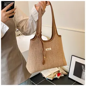 Detailed macro view of woven straw tote bag with brown leather handles and brand logo tag