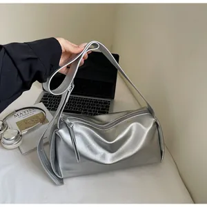 Detail der silbernen Lederkissen-Tasche mit breitem Gurt und Metallic-Finish