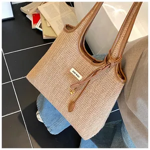 Detail of red striped woven tote bag with brown leather straps and branded logo patch