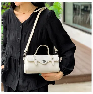 Detail shot of a minimalist white crossbody bag with silver twist lock and shoulder strap