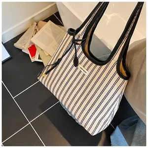 Close-up of striped canvas tote bag with black trim and brand label detail