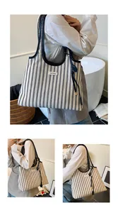 Close-up of black and white striped canvas tote bag with leather handles and brand logo