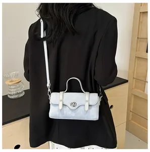 Detail of light blue textured leather crossbody bag with silver twist lock on a model