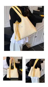 Close-up of yellow striped canvas tote bag showing the tassel detail and logo patch