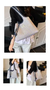 Close-up of a striped canvas tote bag featuring leather handles and a woven logo label