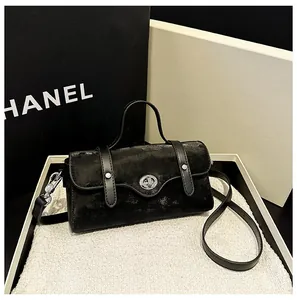 Detail of black textured leather bag featuring a polished silver twist lock and top handle