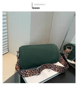 Dettaglio borsa a cilindro verde scuro con tracolla leopardata e accessori in metallo argento
