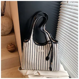 Detail of black and white striped canvas tote bag with leather handles and decorative tag