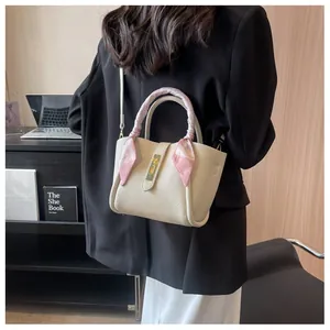 Détail d'un sac seau en cuir beige avec poignée en foulard de soie à l'épaule