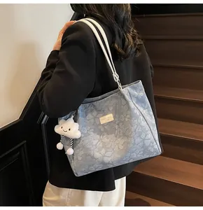 Detail view of light blue floral tote bag with cute cloud charm and leather tag