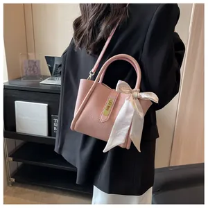 Détail du sac seau rose clair en cuir grainé avec un foulard décoratif en soie