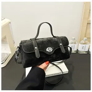 Close-up of black velvet shoulder bag with metal twist lock and leather handle detail