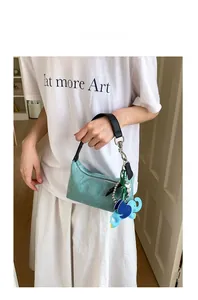 Detail of light blue woven tote bag with black leather handle and cute elephant charm