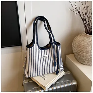 Detail of blue and white striped tote bag with leather handles on travel suitcases