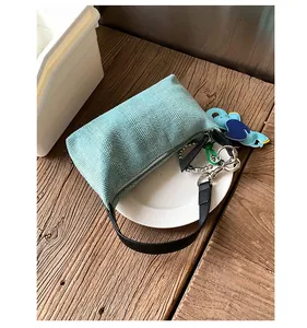 Detail of light blue woven knit bag featuring a navy elephant charm and black leather handle