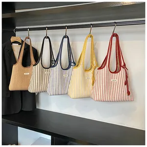 Display of striped canvas tote bags in various colors hanging on a retail store rack