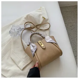 Sac seau kaki avec détail de foulard en soie et fermoir doré sur un blazer blanc