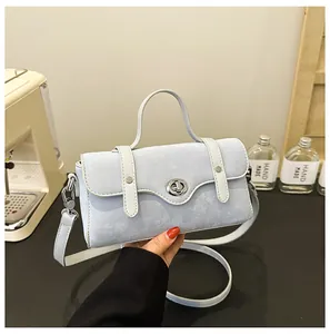 Detail of light blue crossbody bag with silver twist lock and round top handle texture