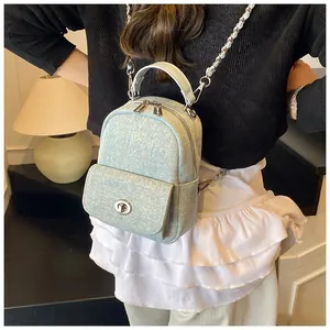 Detail of light blue denim mini backpack with metal chain strap worn by a female model