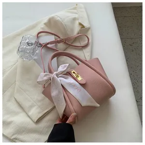 Détail du sac seau en cuir litchi rose avec poignée en soie et fermoir doré