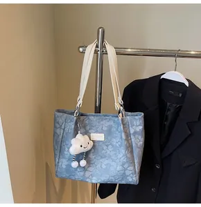 Close-up of light blue jacquard tote bag with floral patterns and plush cloud charm