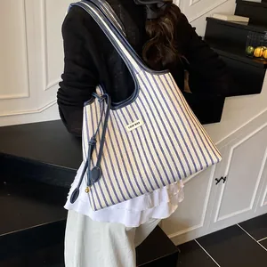 Chic blue and white striped tote bag with leather handles shown in a modern interior