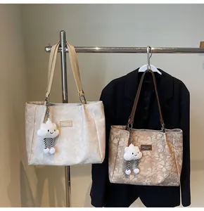 Detail of solid color tote bags with floral patterns and cute cloud-shaped plush charms