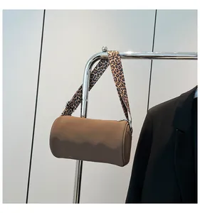 Dettaglio borsa a cilindro marrone con tracolla larga con stampa leopardata