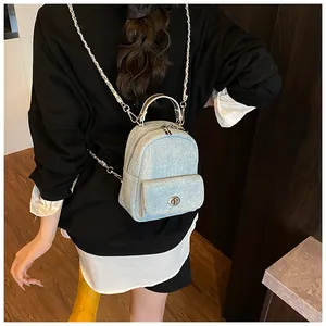 Close-up of a light blue mini denim backpack with silver chain and metal turn-lock detail