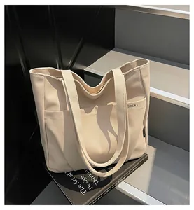 Detail view of cream canvas tote bag with front pocket and durable handle straps