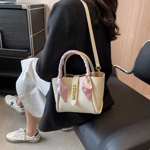 Sac seau minimaliste en cuir beige avec anse en foulard de soie rose et boucle dorée