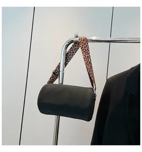 Dettaglio della borsa a cilindro nera con tracolla larga a fantasia leopardata trendy