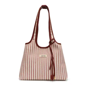 Large red striped canvas tote bag with leather straps and gold bead tassel charm