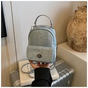 Detail of light blue denim mini bag with silver chain strap and metal rotary buckle