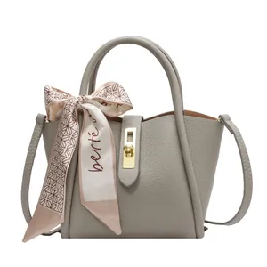 Sac seau gris en cuir grainé avec foulard décoratif en soie et boucle dorée